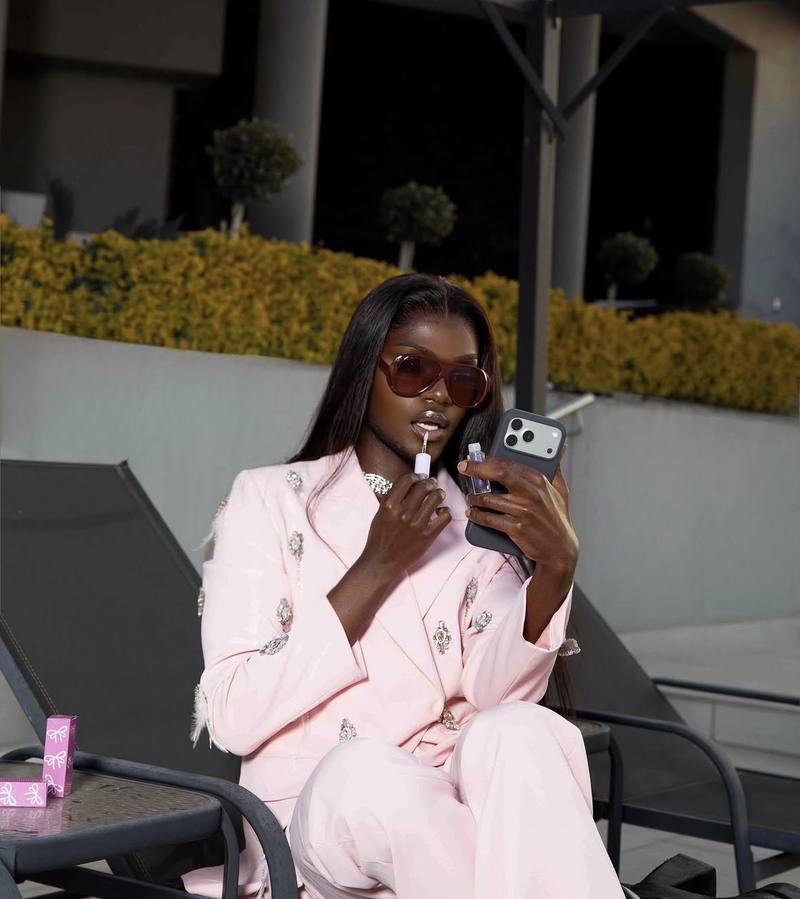 Model in a pink suit applying N Cosmetics lip gloss